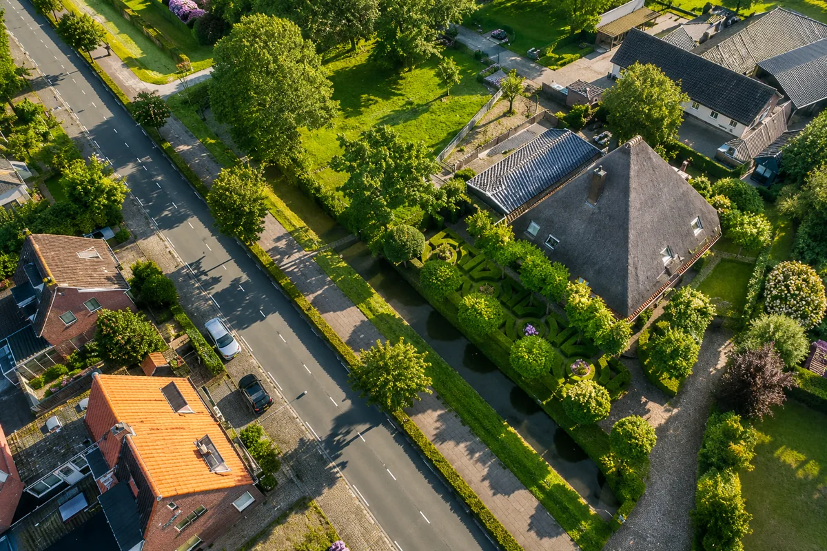 Luchtfoto van de boerderij met het erf, de tuin en de straat ernaast